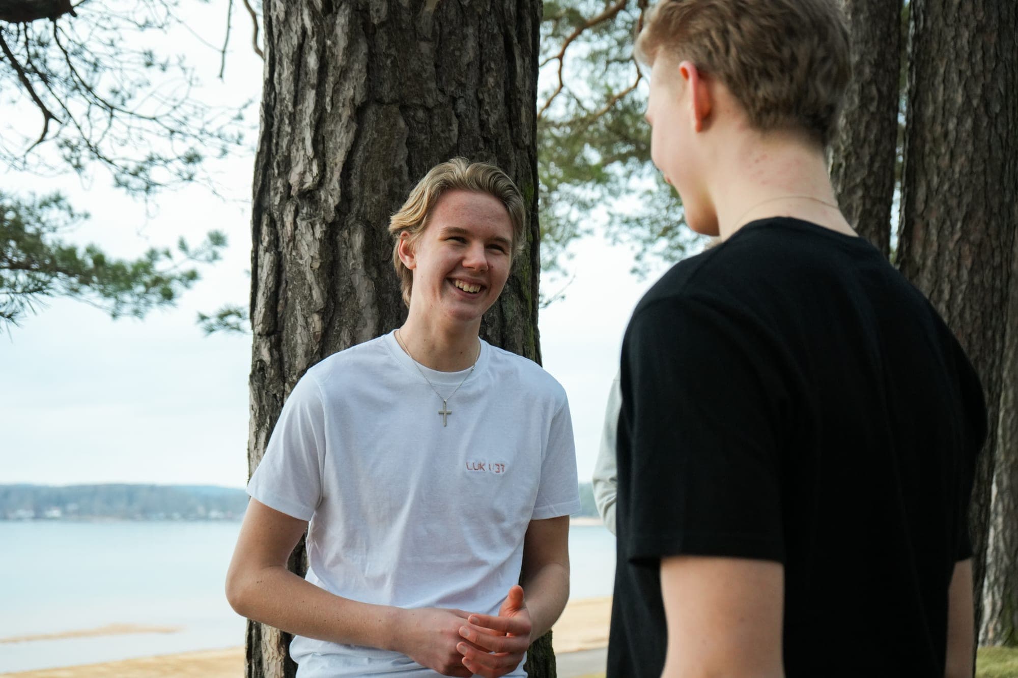 Två killar i broderade EM Brothers-tröjor skrattar tillsammans i skogen